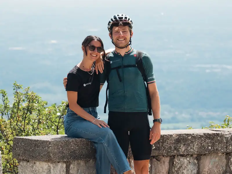 Susi and Benji sitting on a stone wall high above the plain, Benji in his cycling kit